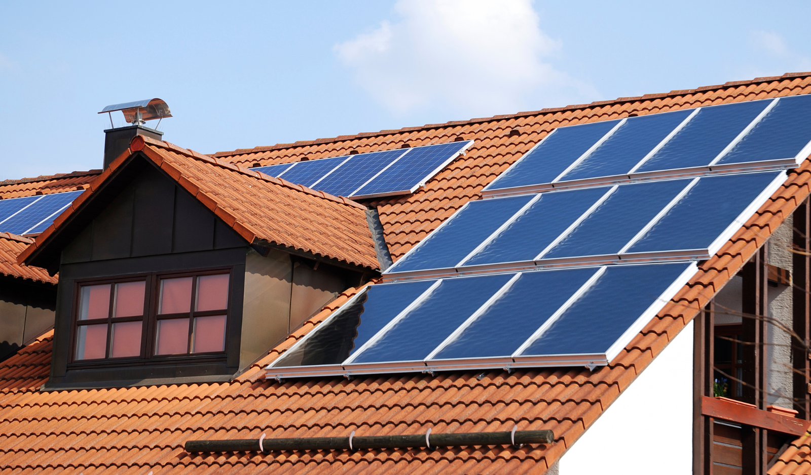 Panouri fotovoltaice montate pe un acoperiș din țiglă la o casă rezidențială.