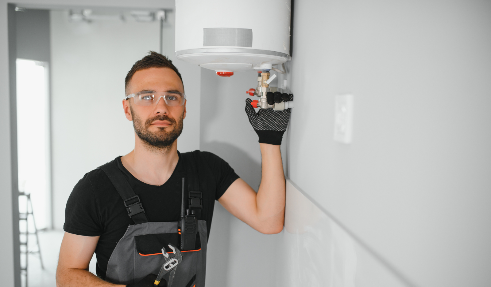 Tehnician service l&acirc;ngă o centrală termică montată pe perete, pregătit să verifice dacă vechea centrală trebuie &icirc;nlocuită