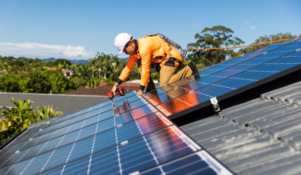 Tehnician autorizat montează panouri fotovoltaice pe acoperișul unei case, instalare sistem solar rezidențial cu microinvertor.