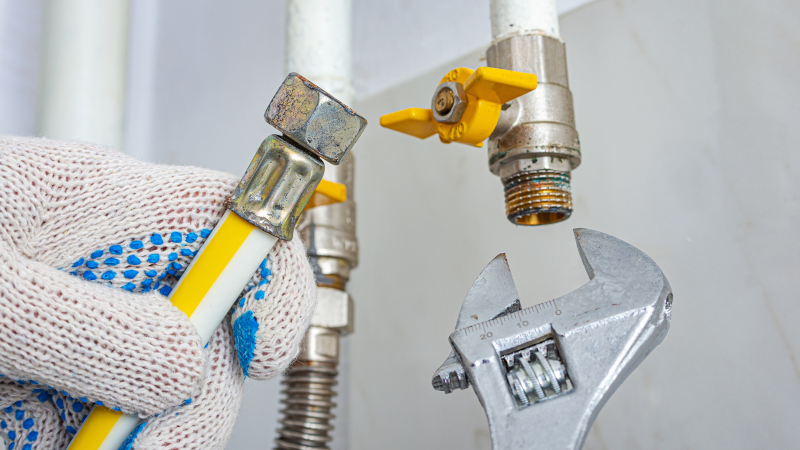 Instalator strânge racordurile instalatiei de gaz cu o cheie reglabilă în timpul reviziei