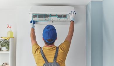 Montaj aparat aer condiționat iarna, tehnician instalează unitate AC pe perete