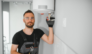 Tehnician service lângă o centrală termică montată pe perete, pregătit să verifice dacă vechea centrală trebuie înlocuită